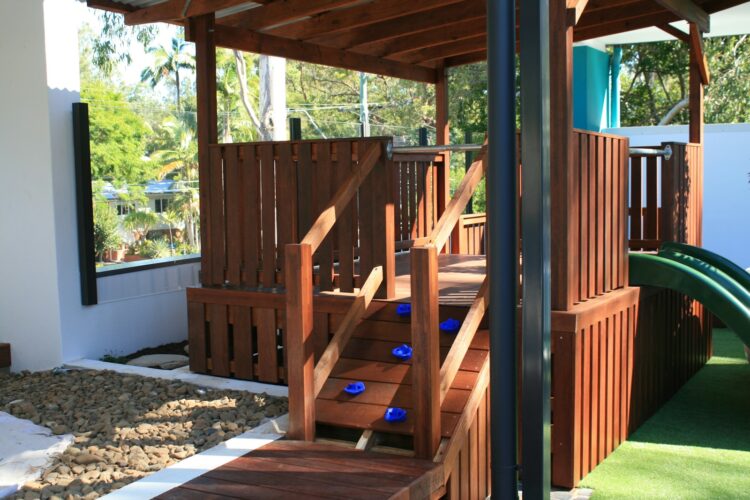 a wooden play structure with a slide in the background